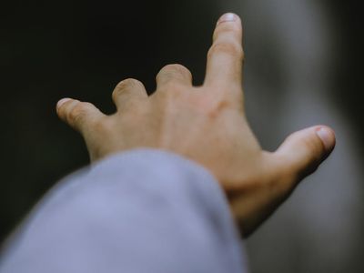 Close up of a hand reaching for a yoga block.