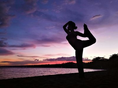 Silhouette of a person doing a balance yoga pose.